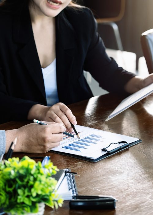 Teamwork concept, consultation, male economist holding pen pointing to budget, finance and investment documents, discussing and planning finances with female advisors in conference room